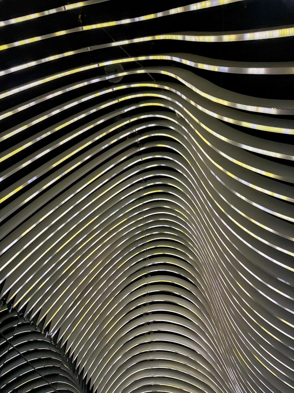 An art deco ceiling of wavy white and yellow lights against a black ceiling, creating an artistic pattern in the lobby of an old hotel