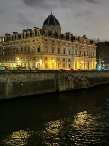 Historic building illuminated at night along the Seine River in Paris, France.