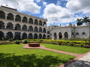 Varendra Research Museum in Rajshahi featuring historic architecture, landscaped gardens, and a lush green courtyard under a bright blue sky.
