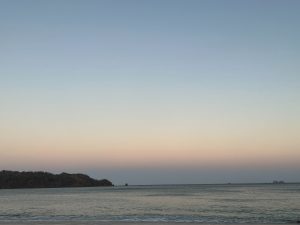 Peaceful beach with calm waves and a pastel sunset sky.
