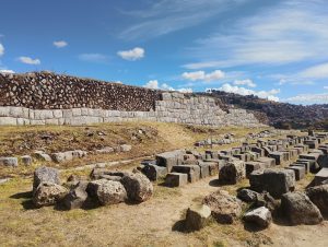 Partially destroyed Inca wall at Sacsayhuaman, near Cusco, Peru. Several partially cut stone blocks lie in front of the remaining wall, offering a glimpse into the construction techniques used by the Incas.