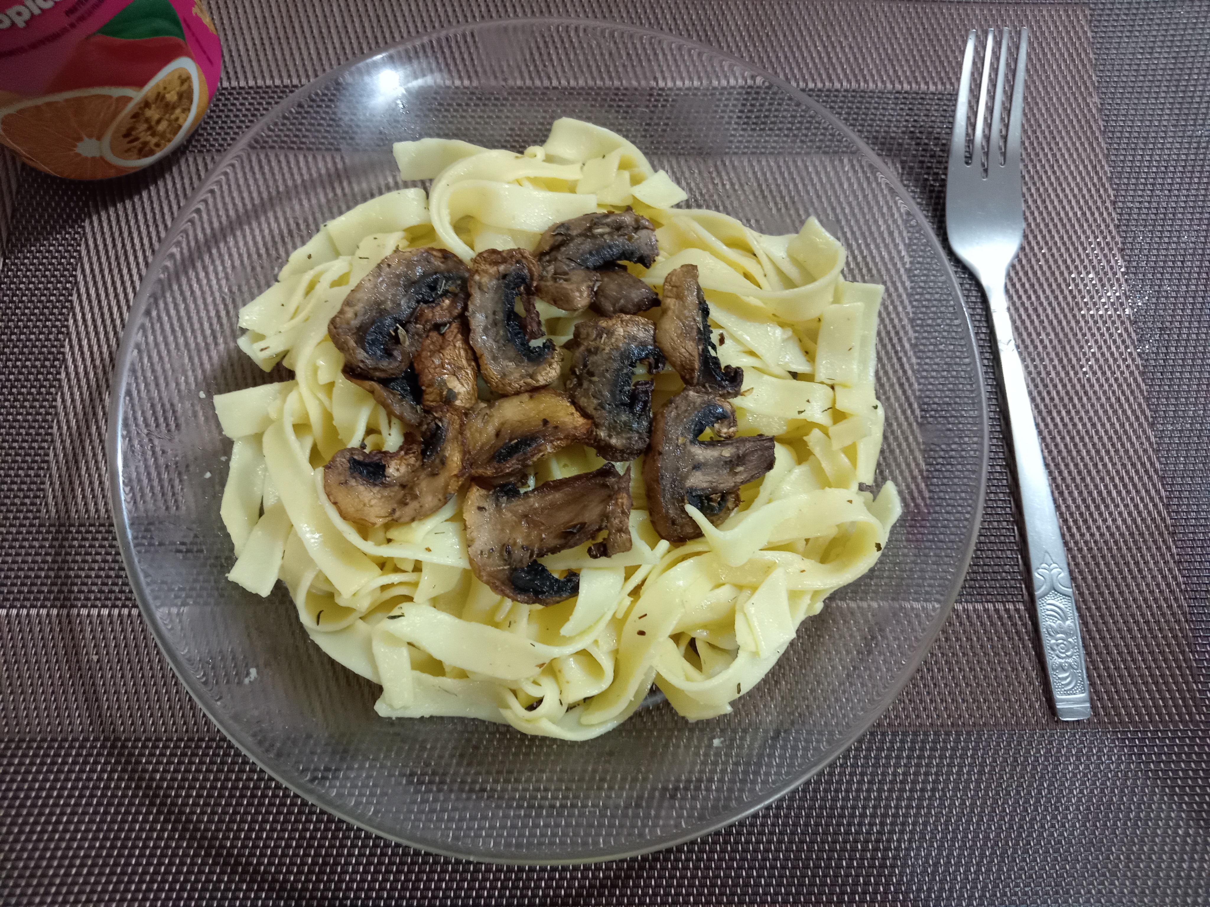 Plate of fettuccine pasta with sautéed mushrooms and a fork.