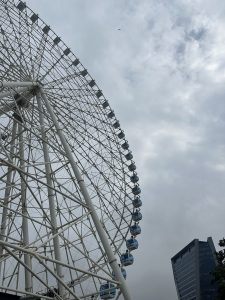 
Large Ferris wheel beside a small building under a cloudy sky.