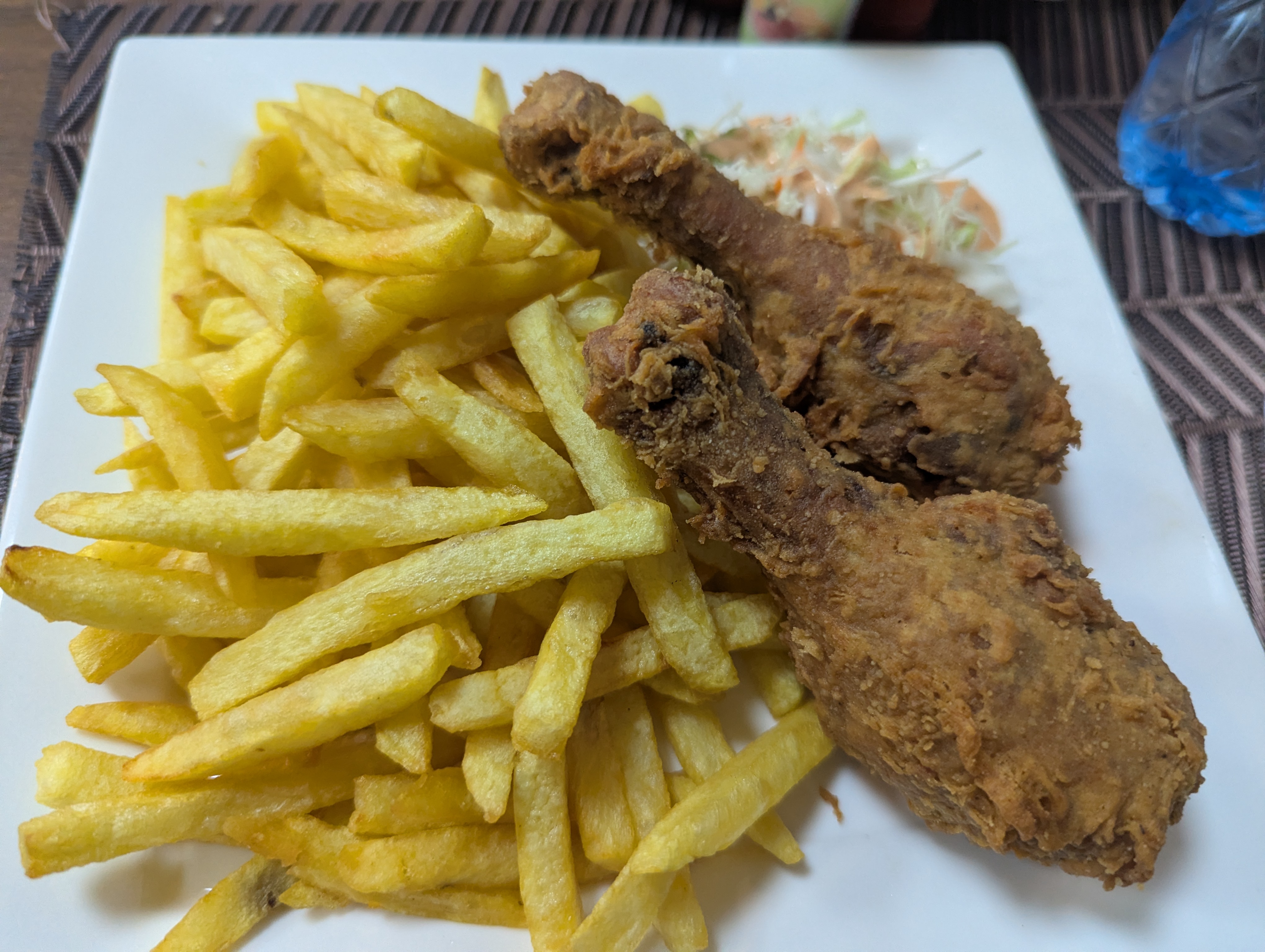 A white square plate features a generous serving of golden, crispy French fries piled high on one side.