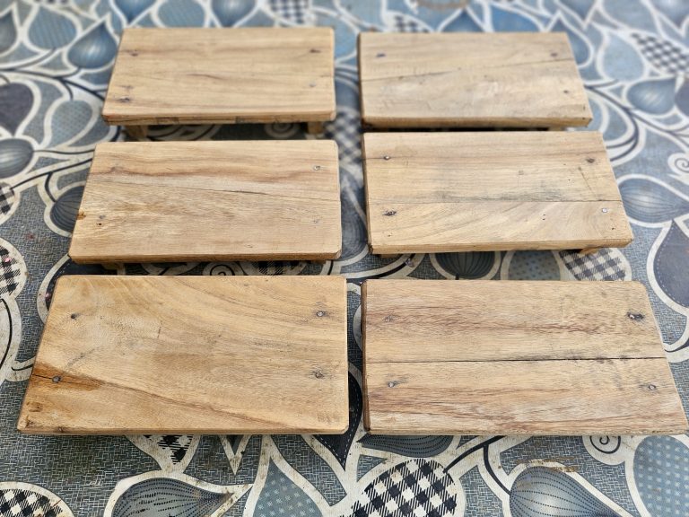 Six handcrafted wooden display stands (wood risers) are neatly arranged, highlighting the natural wood grain and simple design. The image showcases traditional craftsmanship with clean composition. Captured in Pantheeramkavu, Kozhikode, Kerala.