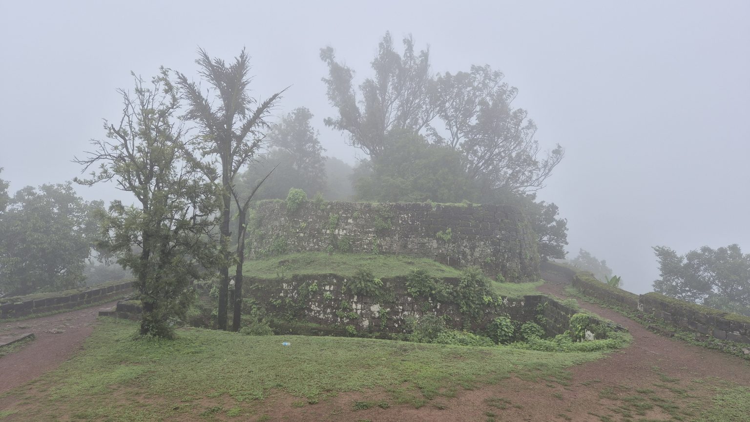 A misty landscape featuring ancient stone ruins set against a backdrop of dense fog.