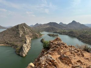 A breathtaking view of rocky hills, calm lakes, and winding waterways under a clear blue sky, offering a peaceful escape into nature.
