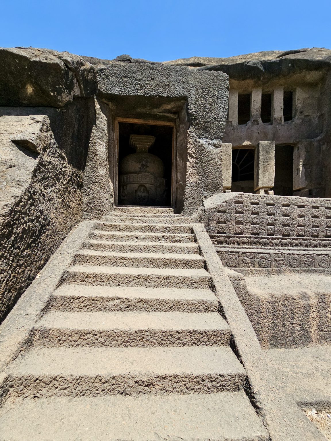 Stone steps lead to the entrance of a cave, where an ancient Buddhist stupa stands. The rock-cut doorway and weathered stone reflect the remarkable history of Kanheri Caves. Captured at Kanheri Caves, Borivali East, Mumbai.