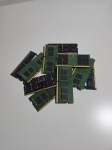 
Several laptop RAM sticks on a light surface with black memory chips and gold connectors.