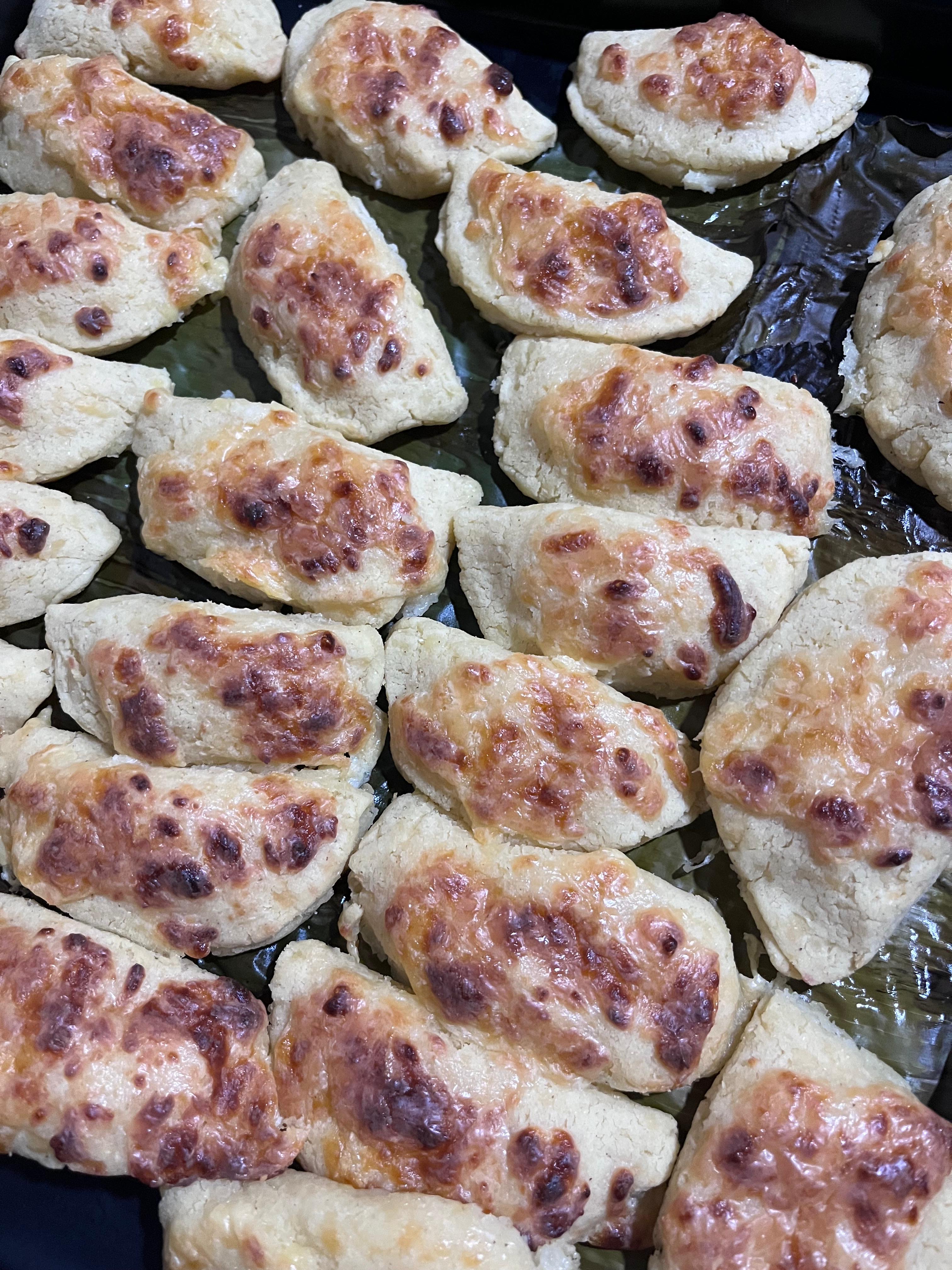 Close-up of golden-brown baked pastries topped with melted cheese.