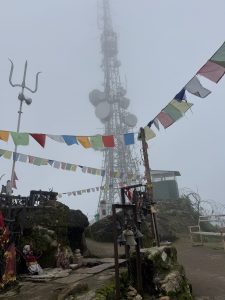 Sacred hilltop with prayer flags and mountain viewpoint.