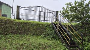 
A metal gate with pointed spikes atop the gate stands at the edge of a grassy slope