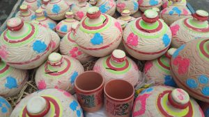 Colorful clay pots and mugs with floral and leaf designs.