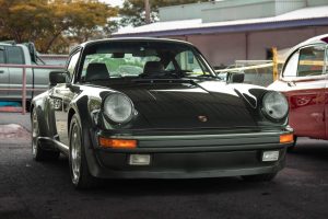
A dark green classic sports car with a sleek design and chrome trim.