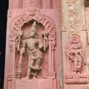 
A stone wall with an intricate carving of a figure in a dynamic pose.