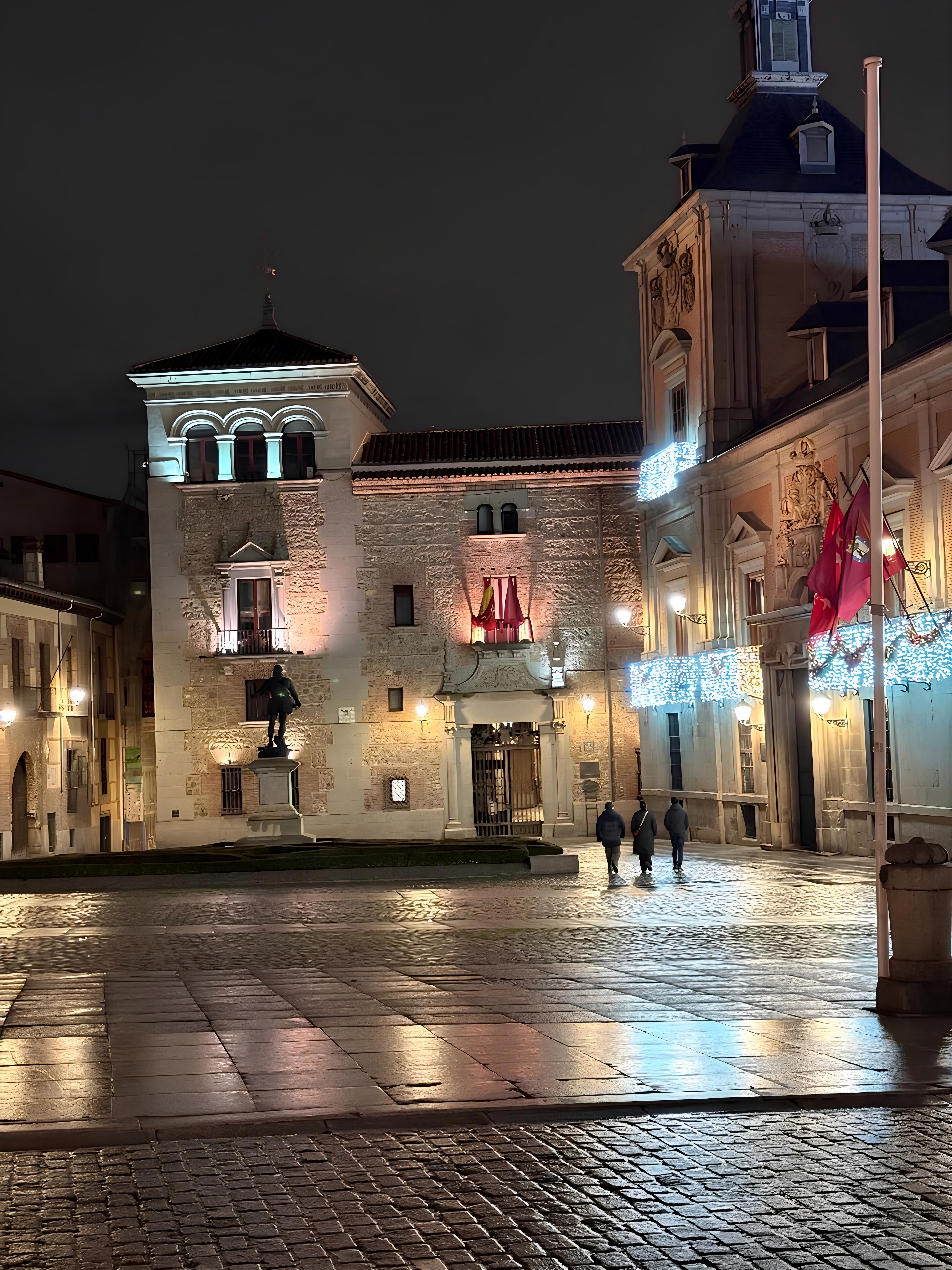 Night view of Plaza de la Villa featuring Casa de la Villa and illuminated historic buildings in Madrid, Spain.