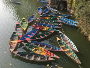 Colorful boats lined up along the shores of Phewa Lake, patiently waiting to welcome travelers to an unforgettable journey.