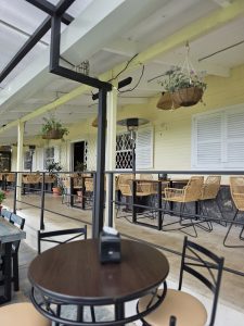
Cozy outdoor café with empty tables, chairs, and hanging plants.