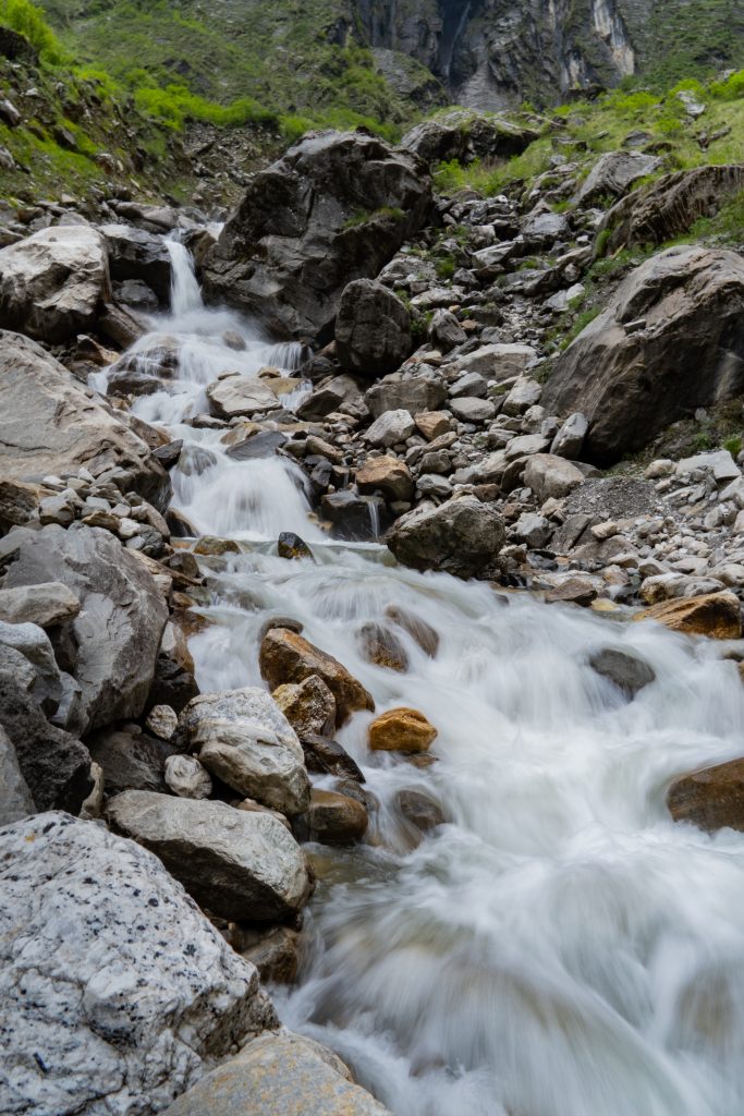 Cascading mountain stream flowing over large boulders in a rocky ravine
