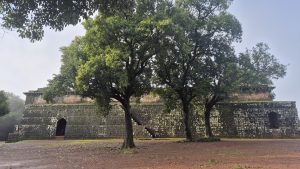 Moss-covered stone fort ruin with trees and a misty forest backdrop.
