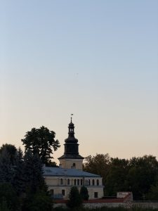 Historic church tower surrounded by trees beneath a peaceful evening sky

