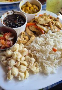 A plate with rice, grilled chicken, black bean dip, fruit salsa, and tomato salsa.