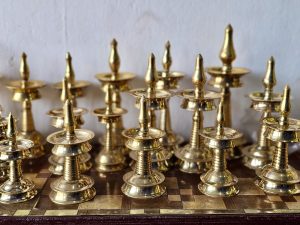 A collection of polished brass oil lamps is beautifully arranged, reflecting warm light and showcasing traditional Indian craftsmanship. The repeating shapes create an elegant display. Captured in Pantheeramkavu, Kozhikode, Kerala.