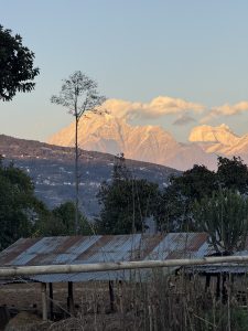 A serene landscape featuring majestic mountains in the background, their peaks dusted with snow and illuminated by the warm light of dawn or dusk.