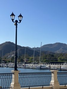 
A marina with a clear blue sky and mountains in the background.