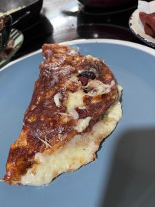 Golden-brown omelet with melted cheese and visible fillings on a light blue plate.