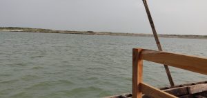 View of a calm river from a wooden boat under an overcast sky.
