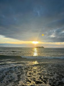 
A sunset over the sea with calm waves and a small island on the horizon.