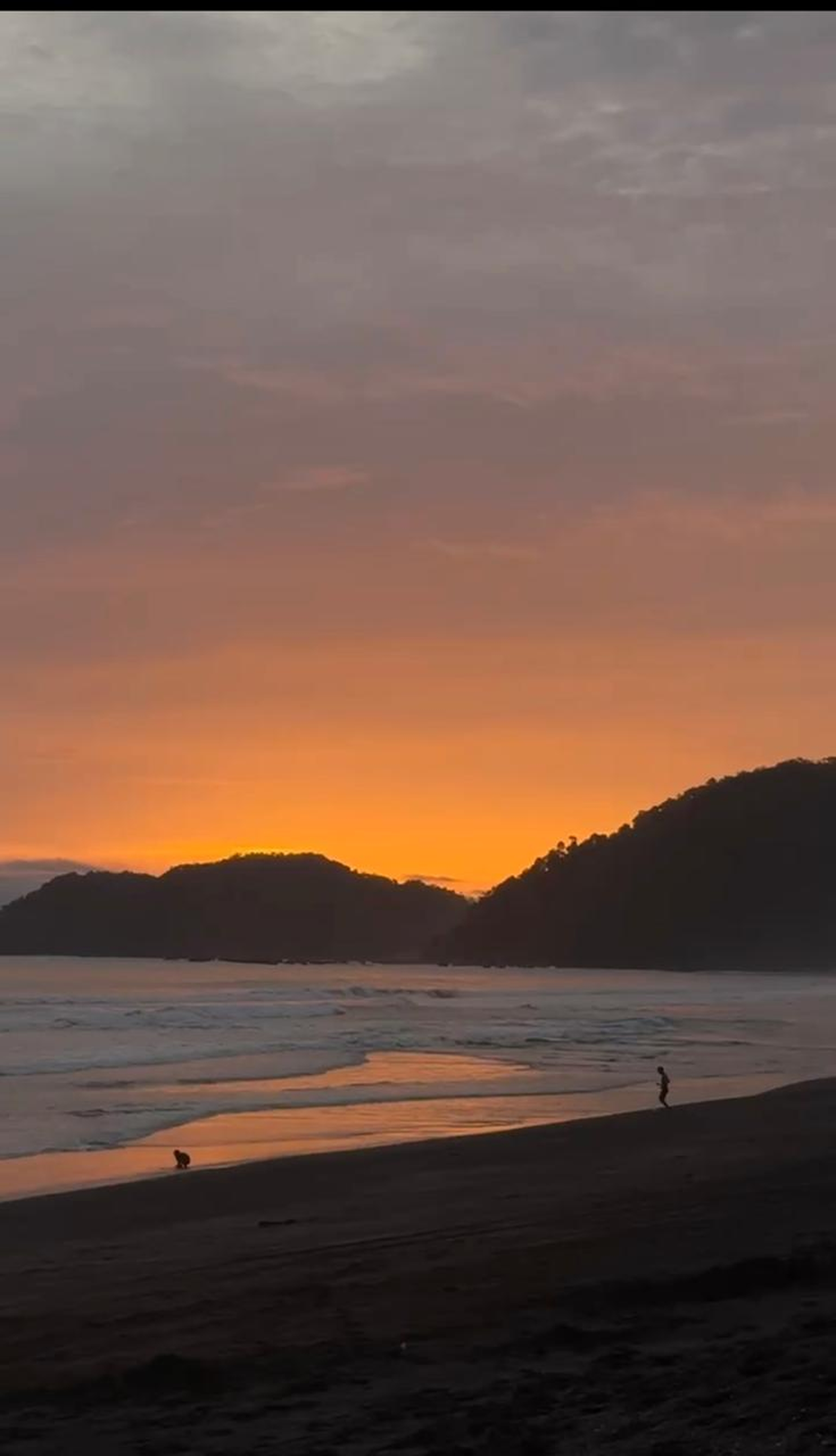A tranquil beach scene at sunset, with soft waves lapping at the shore.