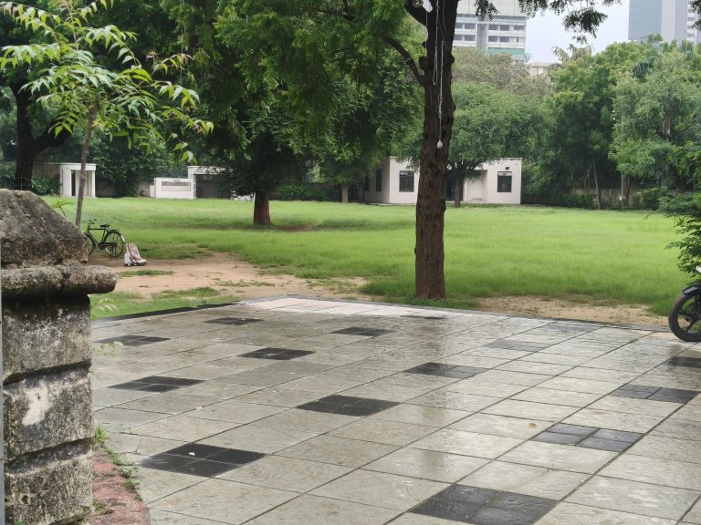 A serene outdoor scene featuring a neatly paved area made of light gray tiles with black accents.