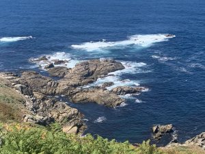 Atlantic Ocean waves and white foam breaking over granite rocks at Cabo Roncudo along the Camiño dos Faros in Galicia.