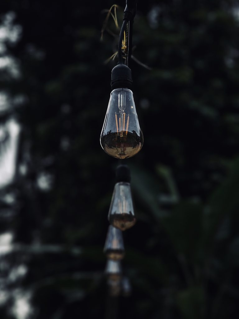 A row of hanging decorative bulbs creates a simple and elegant scene. The sharp focus on the front bulb and the soft blur behind it add depth and mood. Captured in Peruvayal, Kozhikode, Kerala.