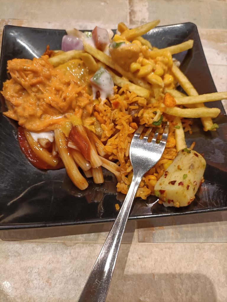 A black square plate holds a colorful mix of food.