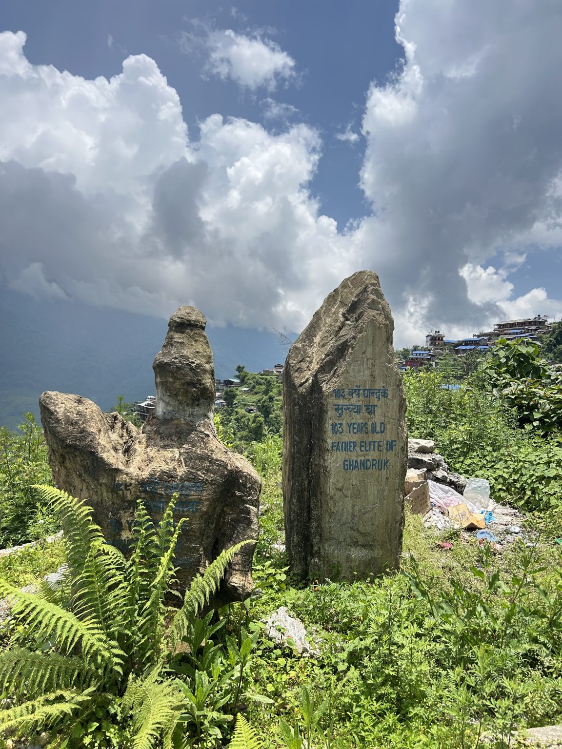 Two large, weathered stone monuments stand amidst lush greenery.