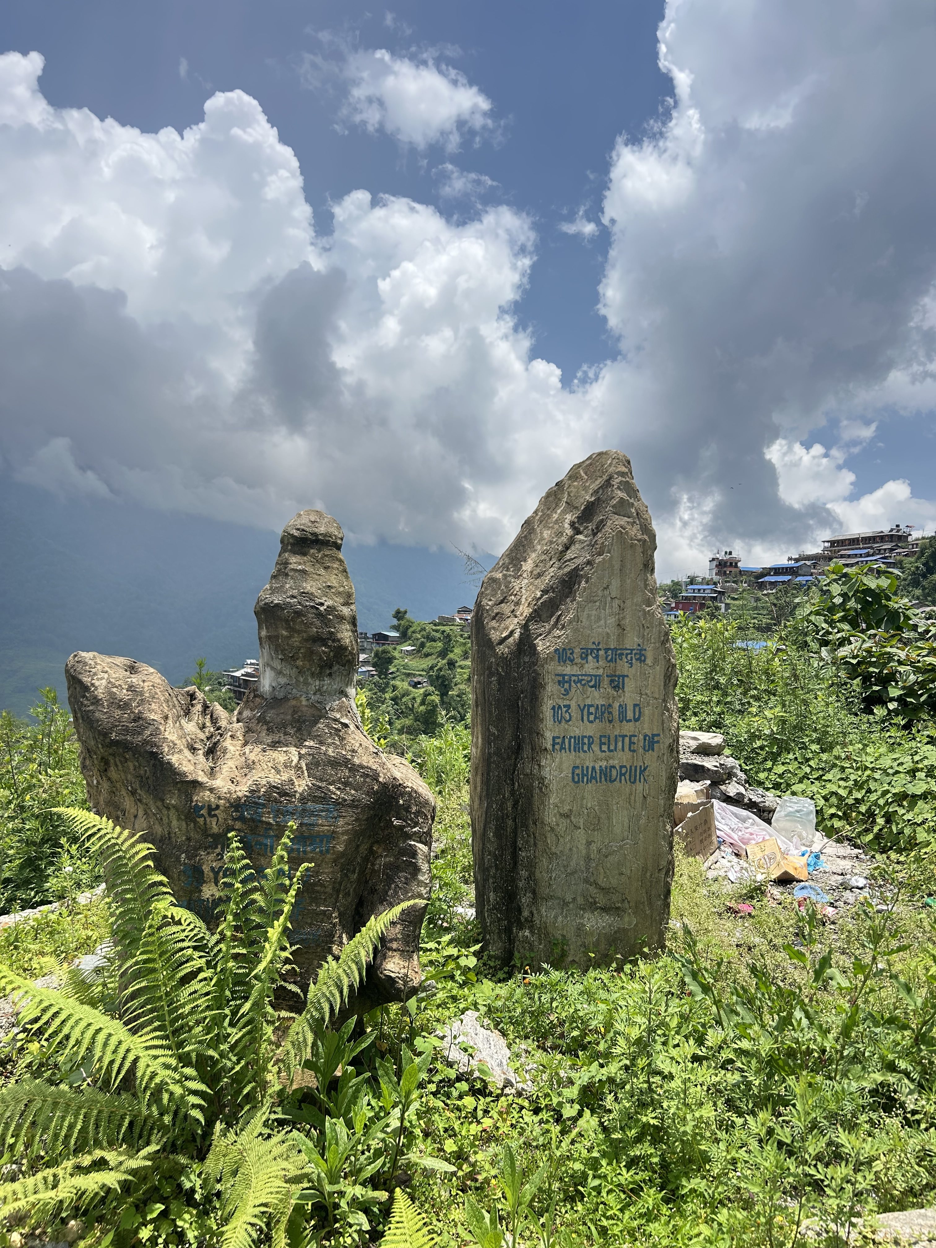 Two large, weathered stone monuments stand amidst lush greenery.