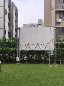 Blank white board decorated with orange, white, and green flags in a grassy outdoor area.