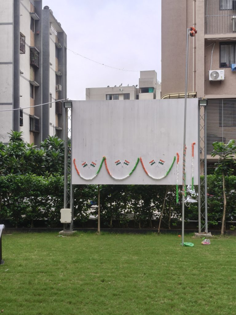 Blank white board decorated with orange, white, and green flags in a grassy outdoor area.