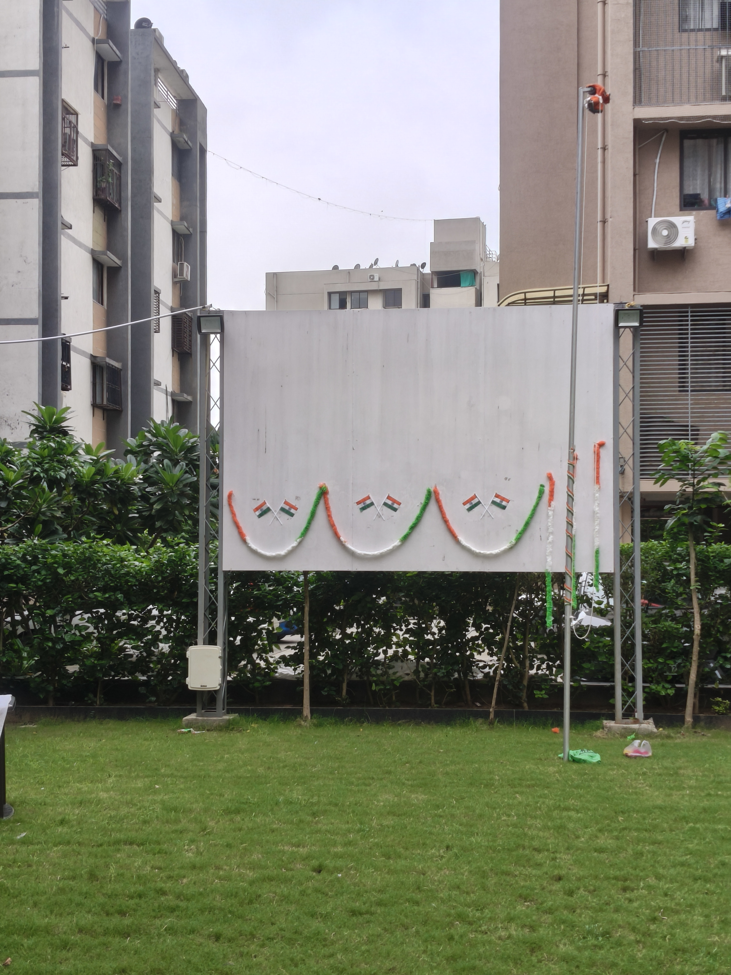 Blank white board decorated with orange, white, and green flags in a grassy outdoor area.