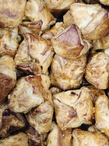 A collection of freshly baked, golden-brown, classic bakery-style egg puffs, a popular flaky pastry snack found across South India, stacked together. Their flaky layers, crisp edges, and varied shapes create a detailed and appetizing food-texture photograph. Location: Pantheerankavu, Kozhikode, Kerala.