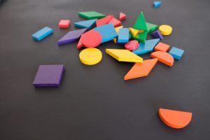 Random, large and small, multi-colored shapes are strewn across a black background. Shapes at the top of the image are slightly out of focus to indicate short depth of field.