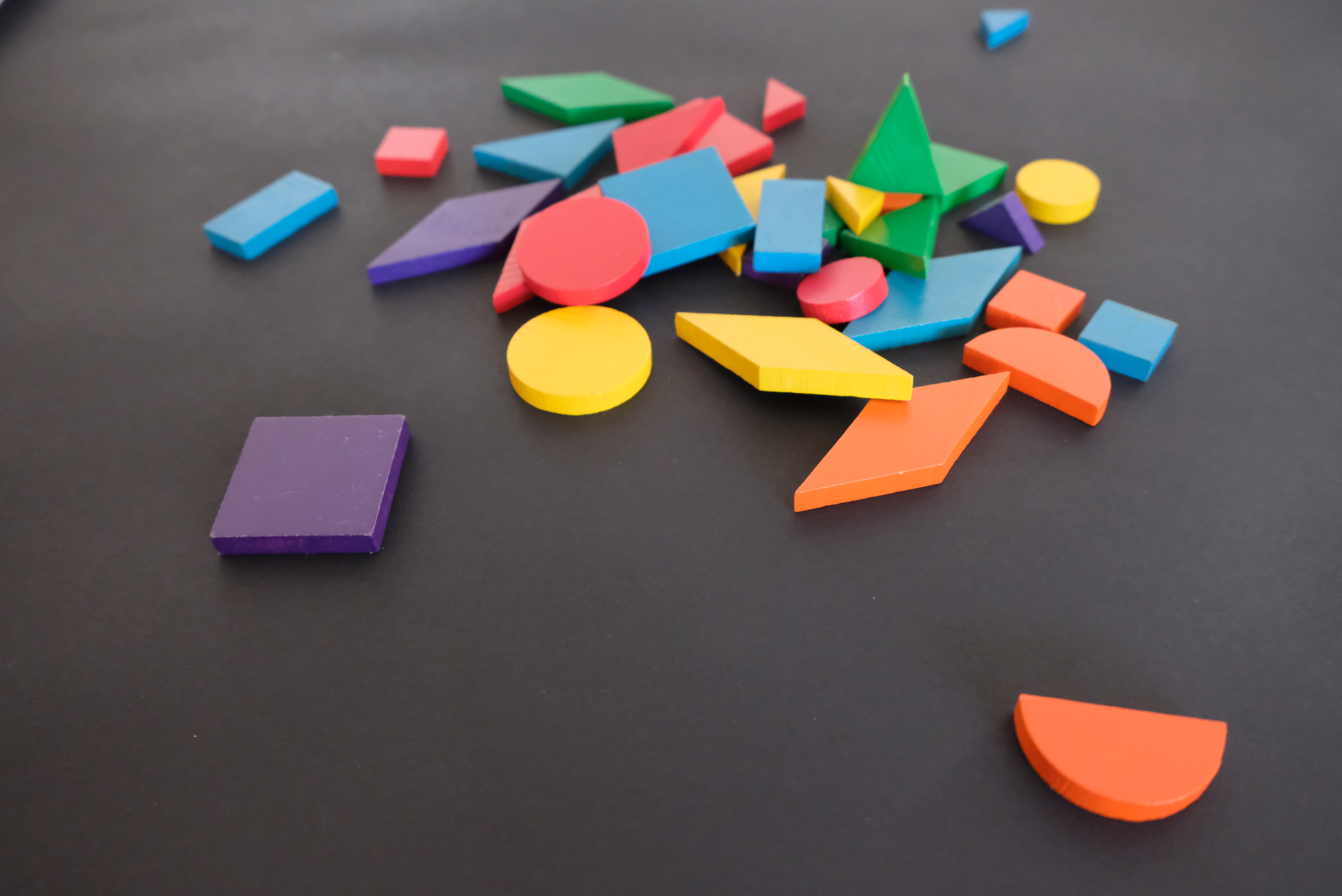 Random, large and small, multi-colored shapes are strewn across a black background. Shapes at the top of the image are slightly out of focus to indicate short depth of field.