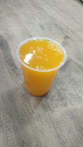 

Plastic cup filled with mango juice on a wooden table