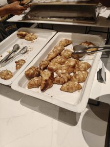 Freshly baked croissants, including almond croissants, served on a buffet tray.
