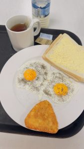

Breakfast with two fried eggs, a hash brown, toast, and a cup of tea.