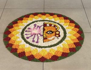 A vibrant circular floral design with a stylized sun-like face, purple rays, and a pink flower at the center.