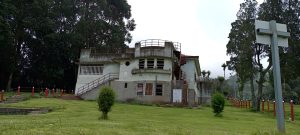Circular tower of a former building at the Sanatorio Durán in Costa Rica, showing a rounded balcony and exterior staircase surrounded by trees.
